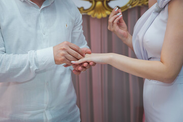 Young man putting ring on finger of his fiancee after marriage proposal, closeup .Wedding hands of a bride and groom . Groom put a ring on finger of his lovely wife.
