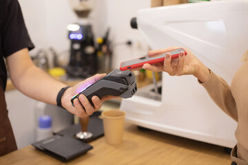Close Up of a Woman Hand Holding a Smartphone with an NFC Payment Technology Used for Paying for Take Away Coffee in a Cafe.