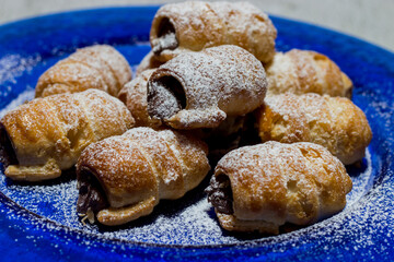 Chocolate cannoli. Italian chocolate sweets on blue plate and white background.