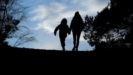 silhouettes of a boy and a girl sky against a blue sky in sunset during the lockdown due to the coronavirus measures