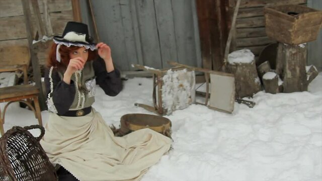 Beautiful girl in ethnic clothes in the yard of an old village house with a rat on her hat