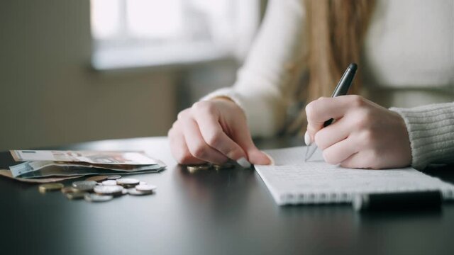 A woman is counting a remaining money, distributing the spending and family budget.Financial difficulties of the young woman. Concept of a living minimum and saving money.Close up.