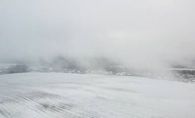 Top view of snow-covered houses in suburb near fields in winter