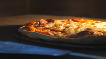 Young cook taking out tasty pepperoni pizza from oven with a shovel at cuisine. Male cook baked delicious dish at kitchen restaurant. Concept of preparing food. Close up Slow motion