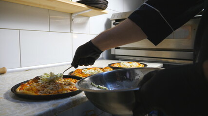 Male hand of cook in glove putting a cabbage mixed in mayonnaise on pita bread using a spoon at kitchen. Chef preparing to serve dish at restaurant. Concept of cooking food. Slow motion
