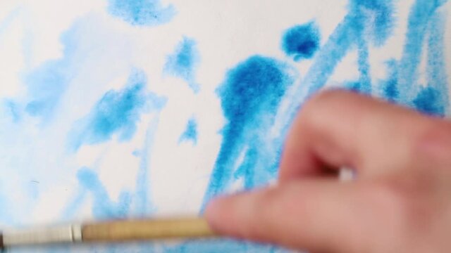 brush strokes of watercolor blue paint with stains on a sheet of white paper. psychedelic concept.