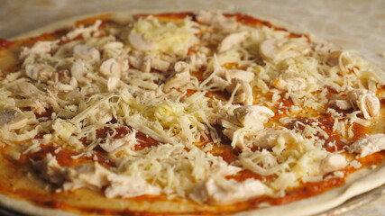 Male hand throwing pieces of mushrooms on pastry in metal form at kitchen. Young cook preparing tasty pizza on a wooden surface at cuisine restaurant. Concept of cooking food. Top view Slow motion