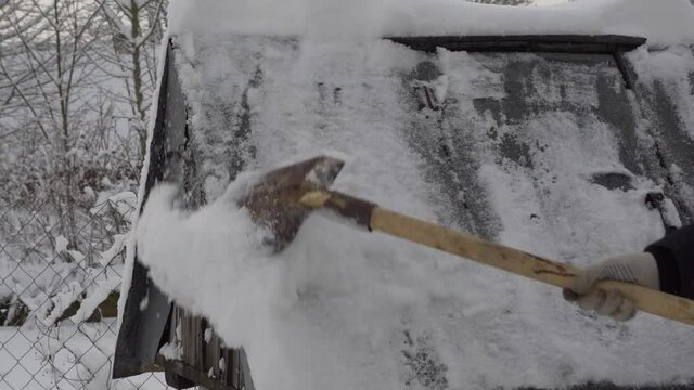 A man cleans snow from a well in the village with a shovel, a lot of snow, winter in the village