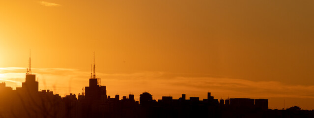 Silhouettes of São José do Rio Preto's skyline during a vibrant orange sunset, capturing the...