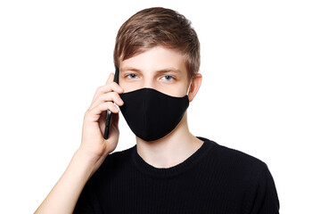 Casual teen boy in black homemade mask and dark sweater talking on phone, isolated on white background.