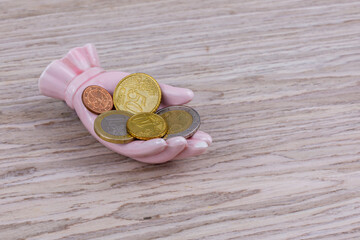 Rosa Porzellanhand mit Euro-Münzen