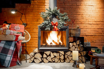 Burning fireplace decorated with a presents and New Year's wreath at cozy home interior