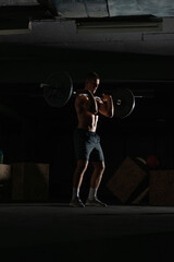 Naklejka na ściany i meble Silhouette of a fit strong shirtless athlete doing squats. Weight lifting workout concept.