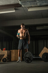 Muscular man taking a break from a hardcore workout while drinking water.