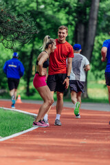 Young couple stretching before starting their morning jogging routine on a tartan track at the park.