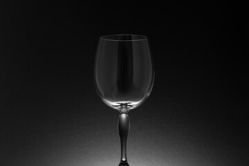 Tallo y cáliz de una copa de cristal vacía sobre fondo negro con iluminación posterior, en clave baja.