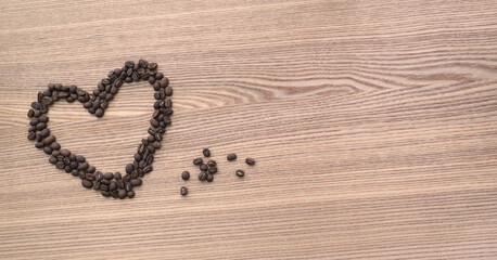Roasted grains of aromatic Arabica are scattered on the heart-shaped countertop. Romantic composition for Valentine's Day.