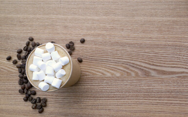 Paper cup of latte coffee with marshmallow on wood table background with sprinkles arabica coffee...