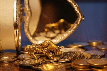 Bull and a stack of coins close-up on the table. In the background is a jewelry box.
