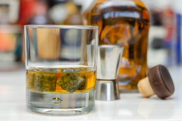 Old fashioned glass with scotch whisky and ice cubes on the bar