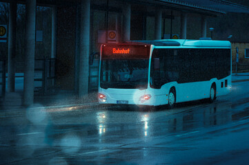 A bus drives to a stop at a bus station in the evening. It is raining. German text means train...
