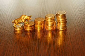 A metal bull and a pile of coins on the table.