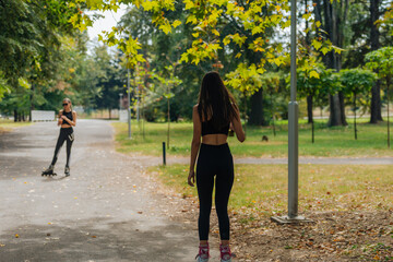 Obraz premium Two women in sportswear rollerblading at the park in sunny weather..