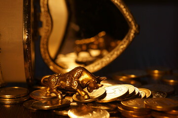 Bull and a stack of coins close-up on the table. In the background is a jewelry box.