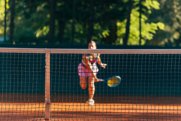 Pretty female tennis player observed through the net.