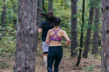 Fit male and female athletes running in nature. Nature and sports concept.