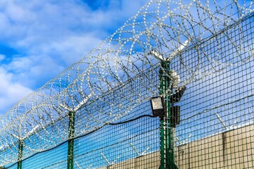 Restricted area - fence with barbed wire. Razor wire jail fence. Barrier border. Boundary security...