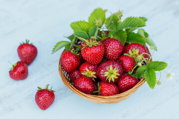 Heap of fresh strawberries in basket bowl on light wooden background. Healthy eating and diet food concept.