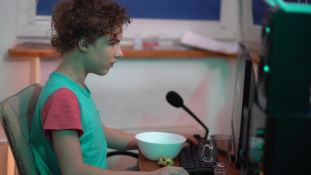 Young boy with gaming headphones looking frustrated at monitor. Video Gamer playing a videogame. A nerdy boy gaming online. Troubled teens