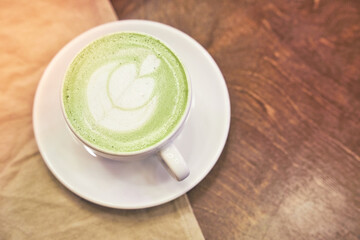 Cup of matcha latte on wooden background and a beige napkin in a cafe with copy space. High quality photo