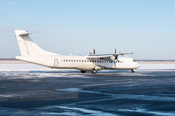 White passenger turboprop aircraft on the airport apron in cold winter weather