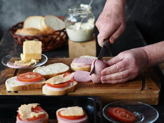 Female hands cutting and arranging ingredients for making hot sandwiches.Healthy homemade food. Confectionery background.