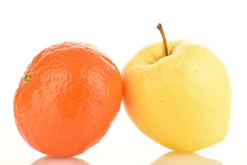 One ripe yellow apple and one tangerine, close-up, isolated on white.