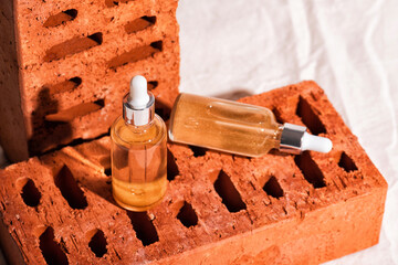 Red bricks podium for advertising cosmetics products with chamomile flowers. Glass of essence or moisturizing serum and camomile. Beige fabric background. Wabi sabi concept
