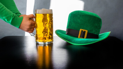 St Patricks day glass beer hand hold costume hat leprechaun black background