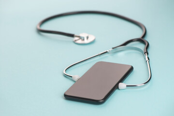 Close-up on a phone with a stethoscope on blue background
