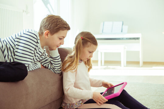 Happy siblings children playing with tablet on floor at home - Powered by Adobe