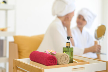 Happy beautiful mom and daughter in white bathrobe applying moisturizing cream on face at home, skin care and treatment concept