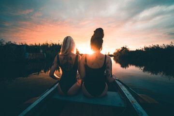 Coppia di ragazze innamorate con tatuaggi sul lago al tramonto 