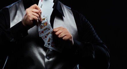 Magician illusionist showing performing card trick. Close up of hand and poker cards on black...