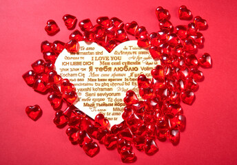 candy in the shape of hearts on a red background. the inscription "I love you" in different languages of the world