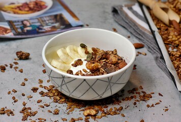 Homemade cocoa granola in white bowl with cashew, almond and seeds on wooden background