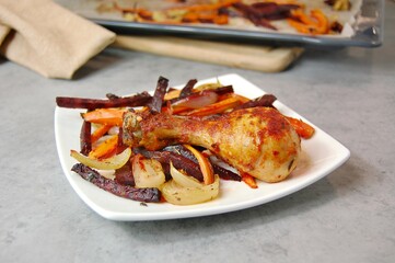 Roasted chicken leg with grilled vegetables carrot, beetroot, onion on white plate