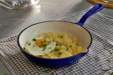 Mashed potatoes with sauerkraut, fried egg and chives in pan
