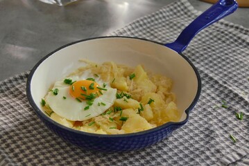 Mashed potatoes with sauerkraut, fried egg and chives in pan