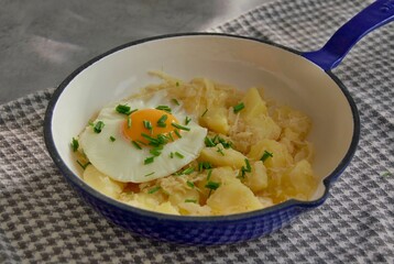 Mashed potatoes with sauerkraut, fried egg and chives in pan